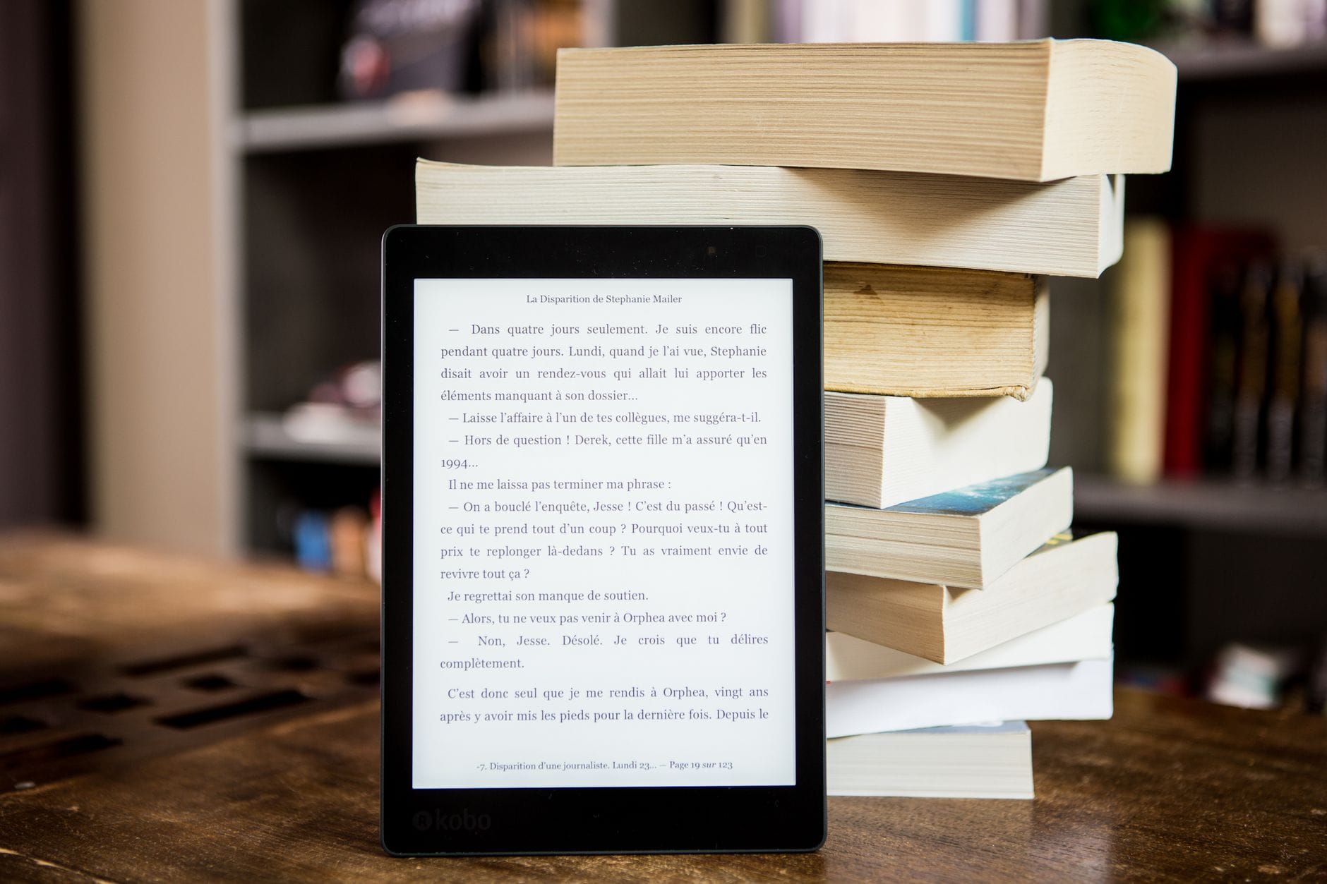 Czytnik e-booków obok stosu książek papierowych na drewnianym stole Czytnik e-booków obok stosu książek papierowych na drewnianym stole